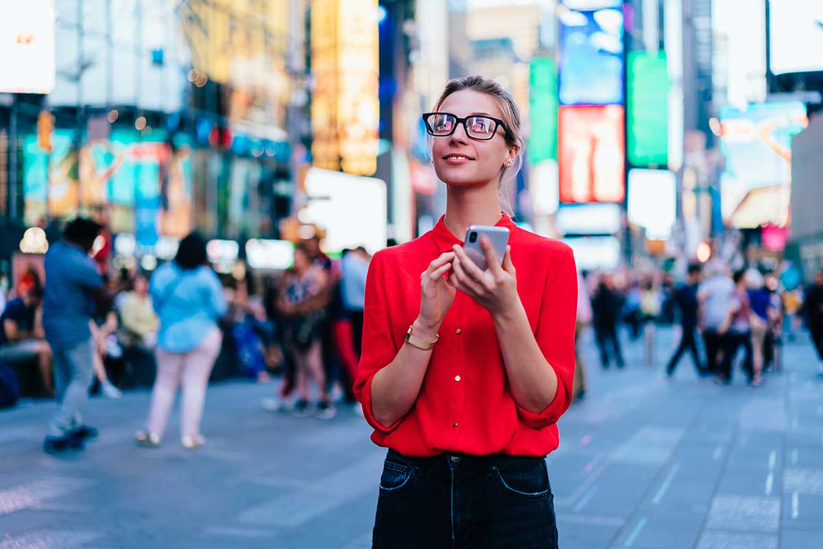 White female standing in Times Square, looking up from her phone to see that good design matters as she's inundated with visuals.